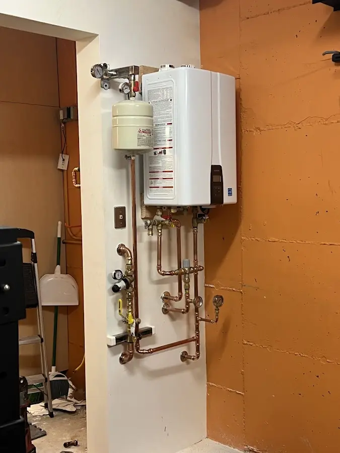 Plumbing technician inspecting water heater connections in Portales